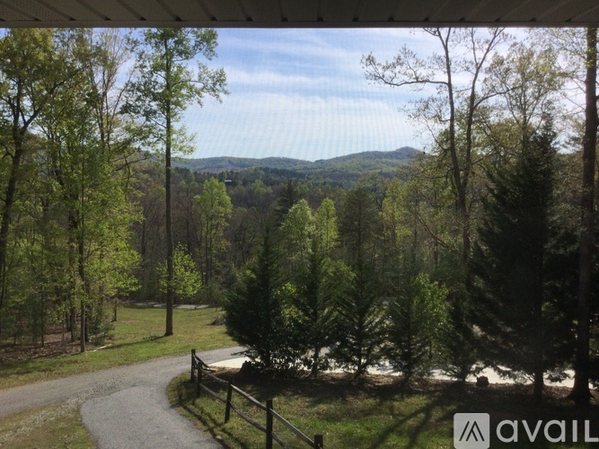 A view from a covered porch looking out at a forest and a mountain in the distance.