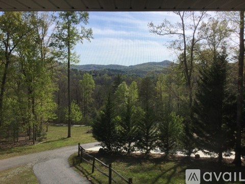 A view from a covered porch looking out at a forest and a mountain in the distance.