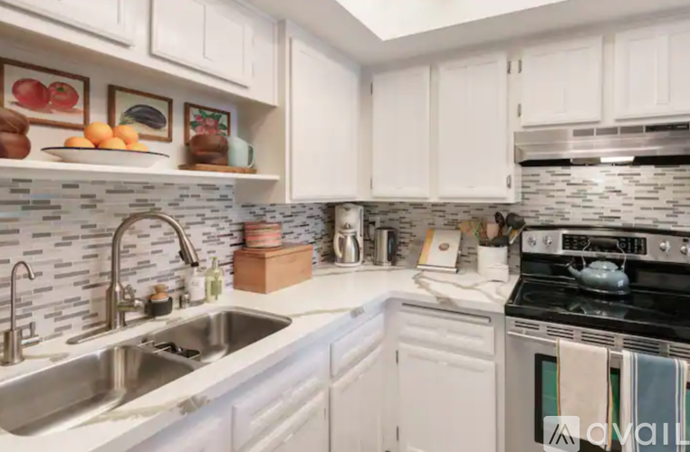 A kitchen with white cabinets and a black and white tiled backsplash.