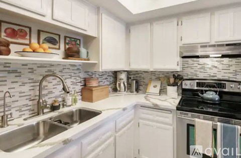A kitchen with white cabinets and a black and white tiled backsplash.