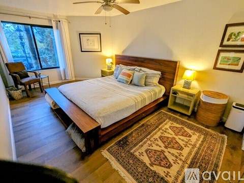 A bedroom with a large bed and a rug on the floor.