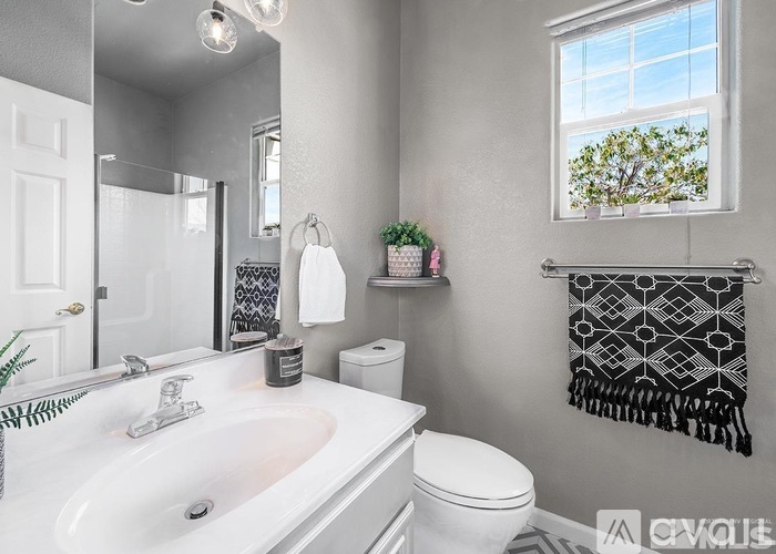 A bathroom with a white sink, toilet, and a window with a view of trees.