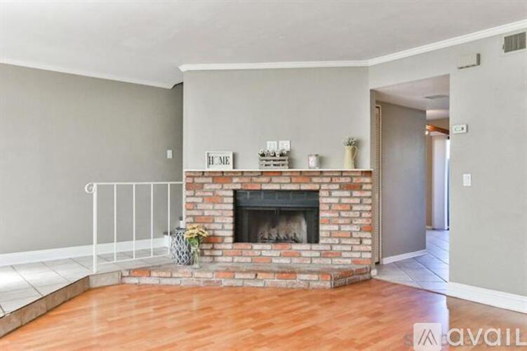 A living room with a fireplace and a vase of flowers.