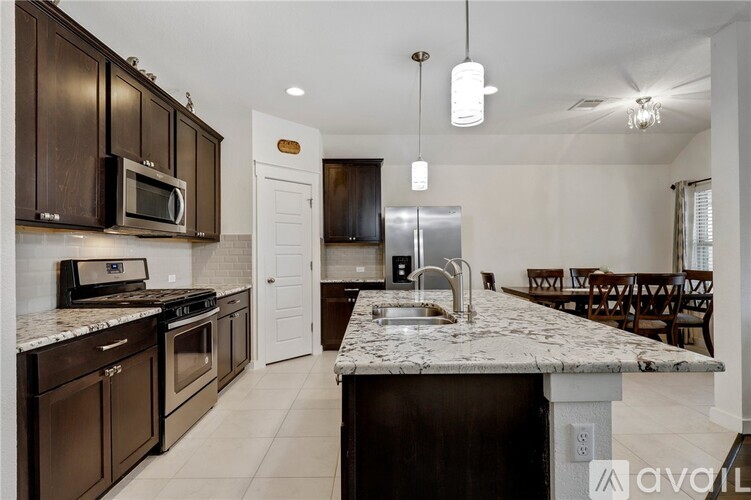 A kitchen with dark brown cabinets and a granite countertop.