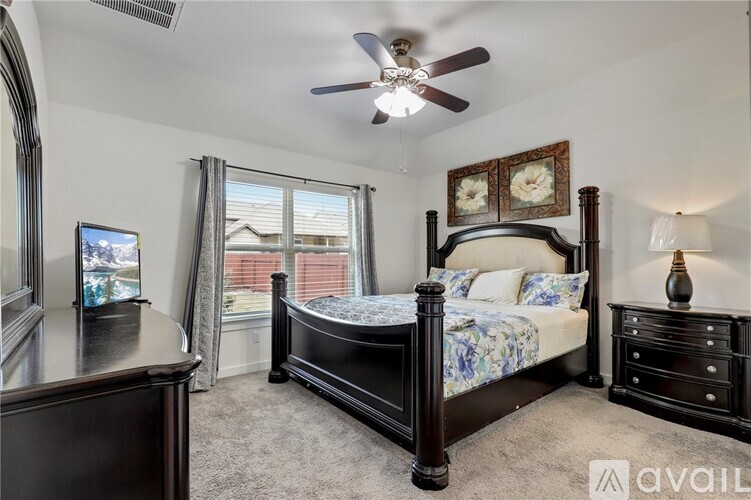 A bedroom with a large bed, a dresser, and a ceiling fan.
