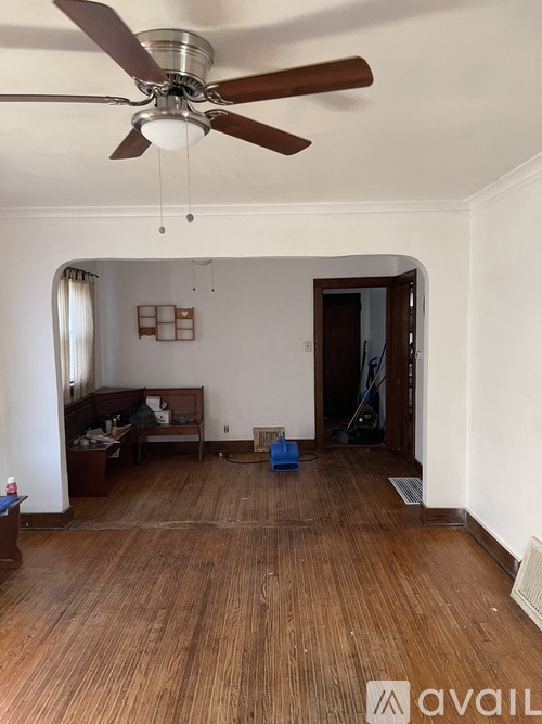 A room with a ceiling fan and wooden flooring.