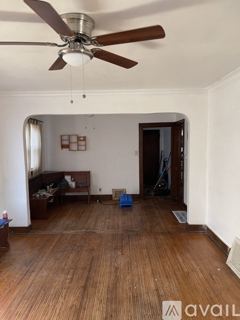 A room with a ceiling fan and wooden flooring.