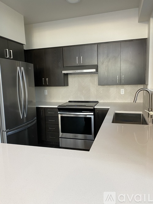 A modern kitchen with a stainless steel refrigerator and oven.