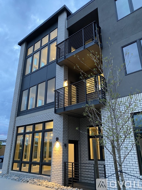 A modern building with a balcony and a tree in front.