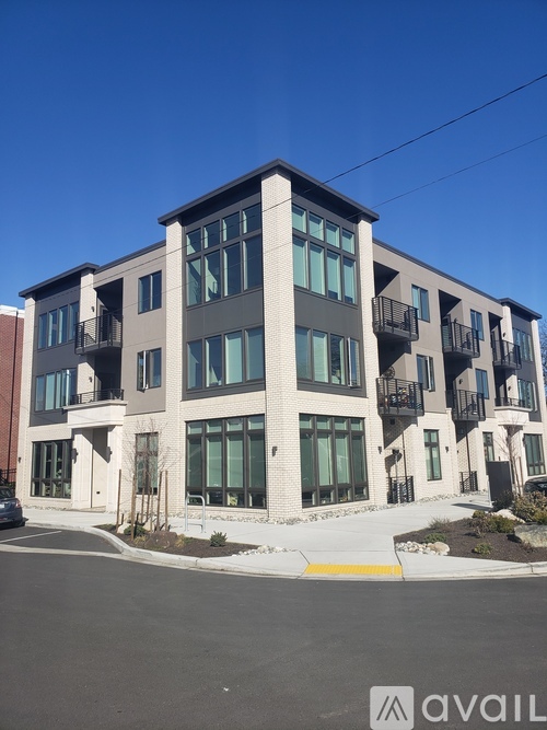 A modern multi-story building with balconies and a clear blue sky above.