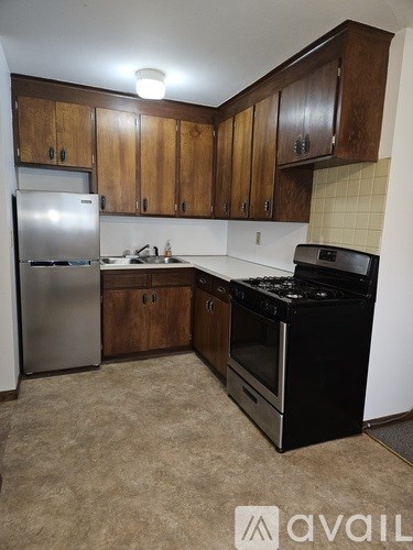 A kitchen with a black stove top oven and a silver refrigerator.