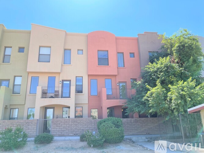 A row of colorful townhouses with balconies and trees in front.
