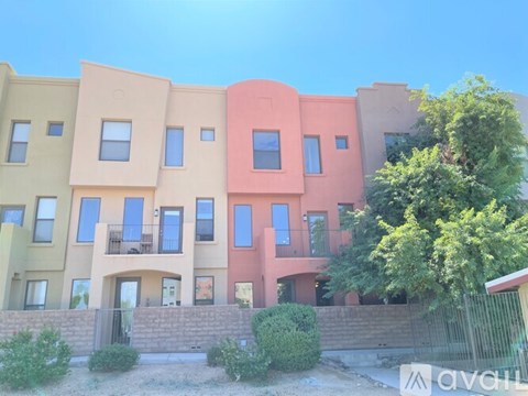 A row of colorful townhouses with balconies and trees in front.