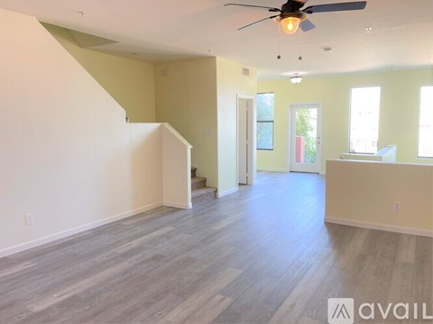 A spacious room with a staircase and a ceiling fan.