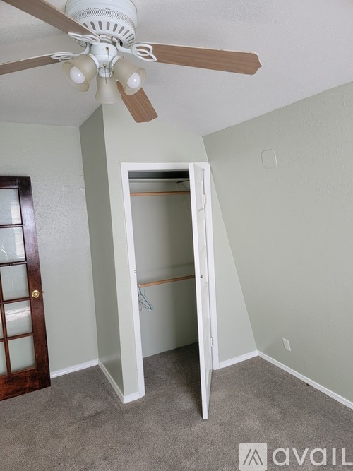 A room with a ceiling fan and a doorway leading to another room.
