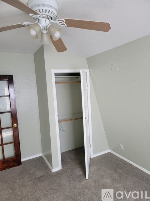 A room with a ceiling fan and a doorway leading to another room.