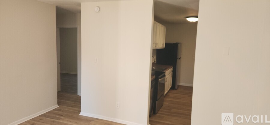 A kitchen area with a black fridge and wooden floors.