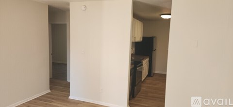 A kitchen area with a black fridge and wooden floors.