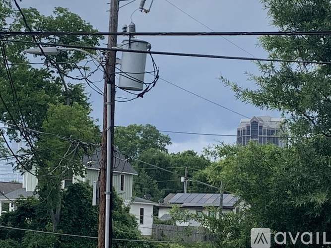 A street view with houses, trees and a power pole with wires.