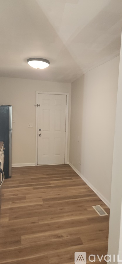 A room with a white door and wooden flooring.