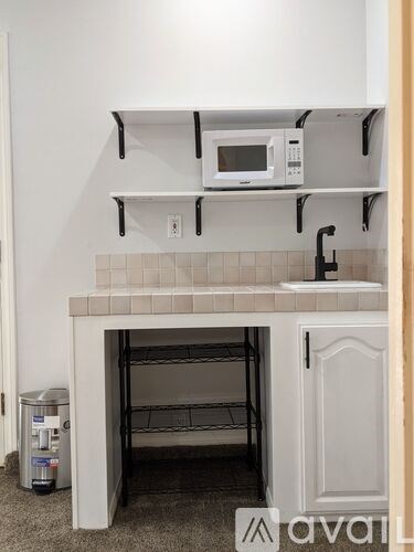 A kitchen with a white oven and microwave on the shelf.