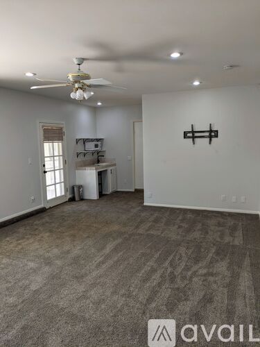 A spacious room with a ceiling fan and a shelf unit.