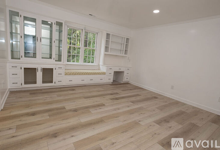 A spacious room with wooden flooring and white walls.