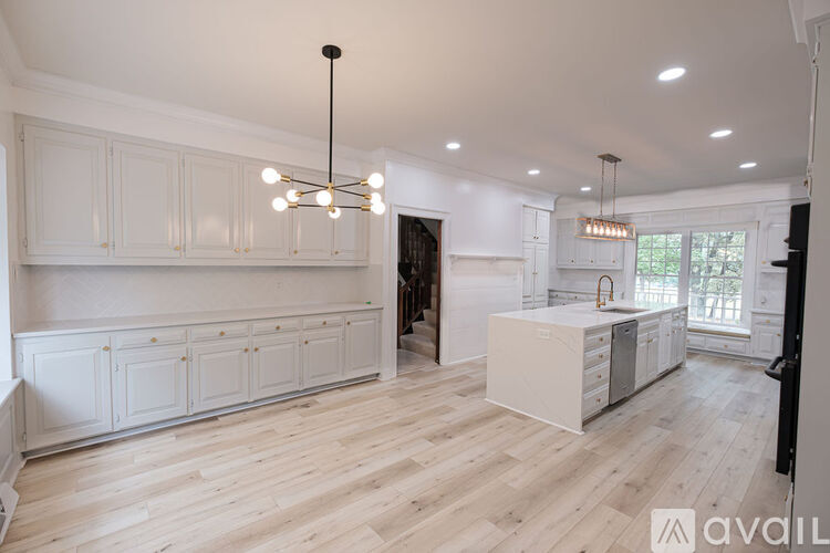 A kitchen with white cabinets and a wooden floor.
