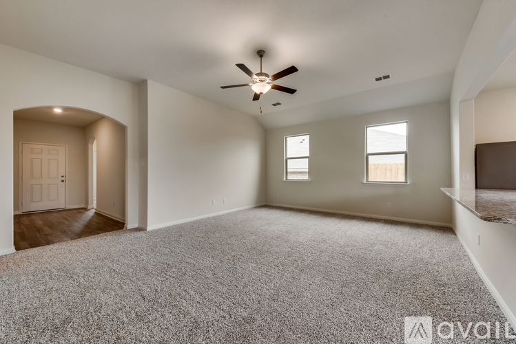 A spacious room with a ceiling fan and carpeted floor.