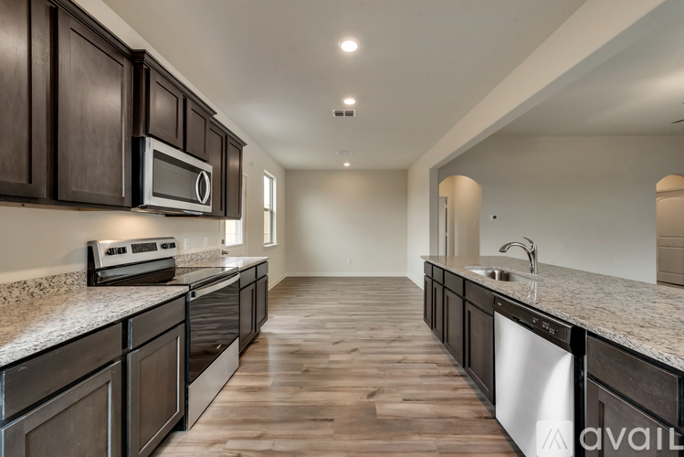 A kitchen with dark wood cabinets and a granite countertop.