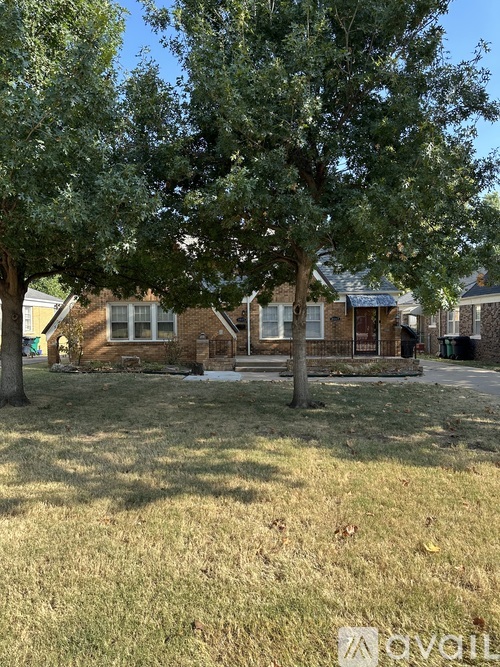A grassy area with trees and houses in the background.