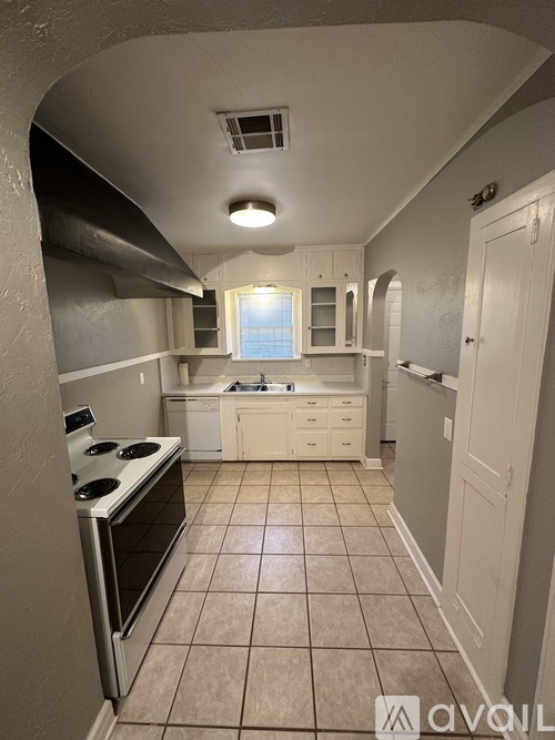 A kitchen with white cabinets and a stove top oven.