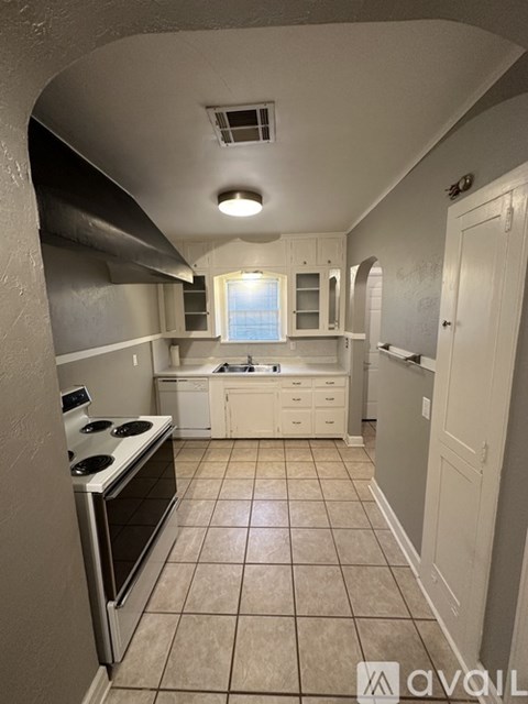 A kitchen with white cabinets and a stove top oven.