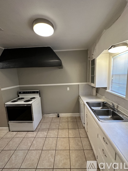 A kitchen with a stove, sink, and cabinets.
