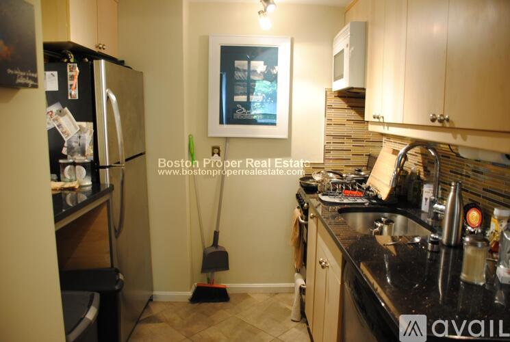 A kitchen with a refrigerator, sink, and cabinets.