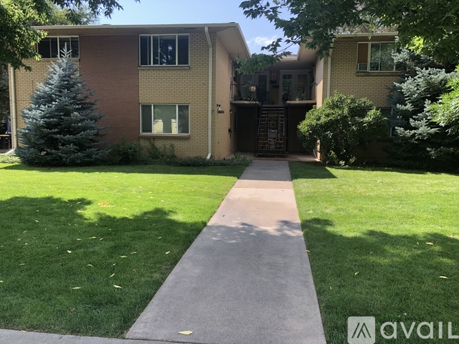 A residential building with a green lawn and a concrete pathway leading to the entrance.