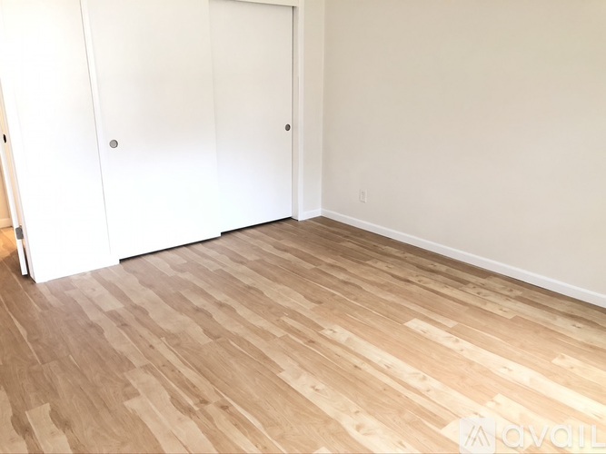 A room with a white door and wooden flooring.