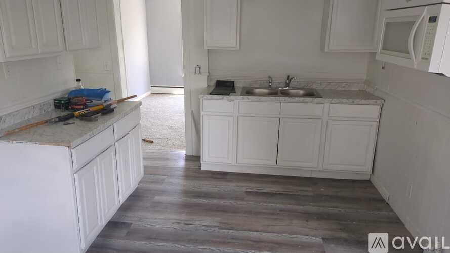 A kitchen with white cabinets and a countertop is available for rent.