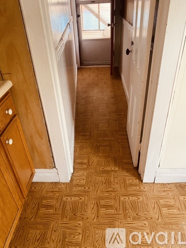 A hallway with a wooden floor and white walls.