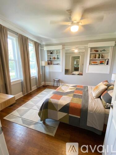 A bedroom with a bed, a window with curtains, and a ceiling fan.