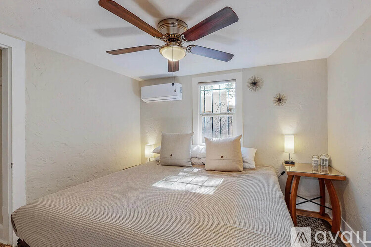 A bedroom with a bed, a ceiling fan, and a window.
