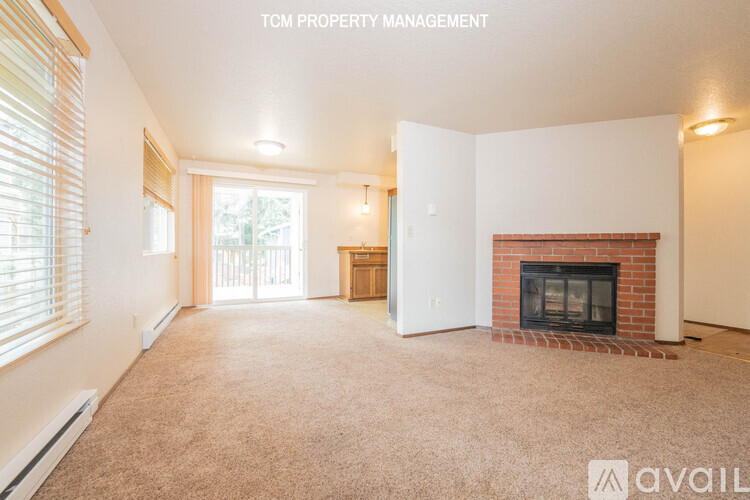 A living room with a fireplace and a carpeted floor.