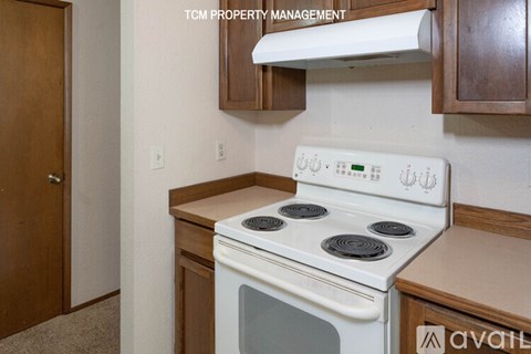A white stove in a kitchen with wooden cabinets and a door to the left.