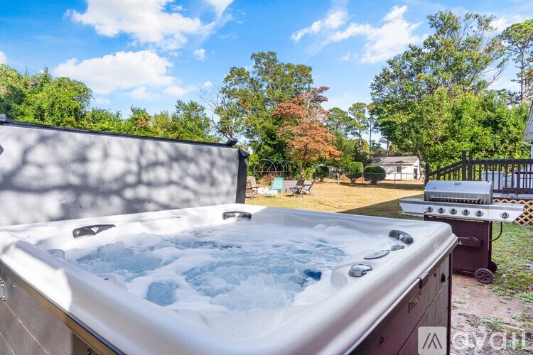 A hot tub is in the foreground with a backyard and trees in the background.