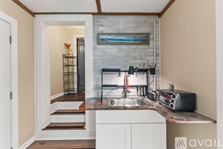 A kitchen with a sink, stove, and a counter with a toaster on it.