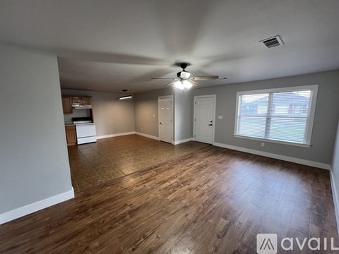 A spacious room with wooden flooring and a ceiling fan.