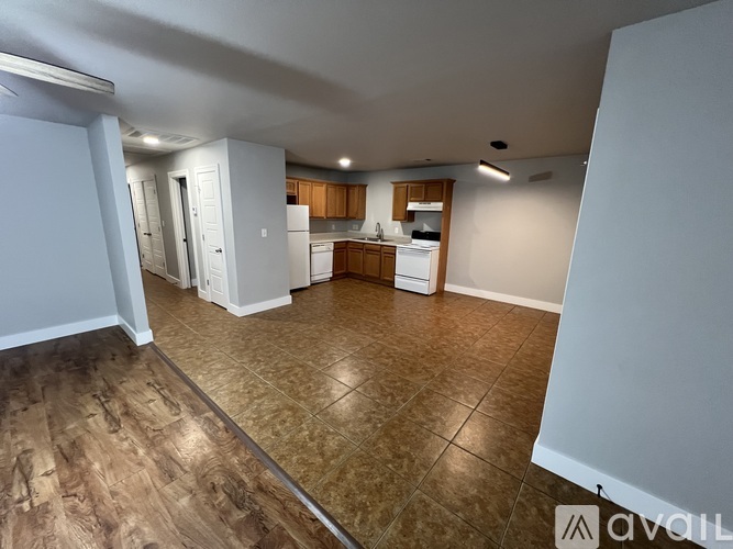 A kitchen area with wooden flooring and white appliances.