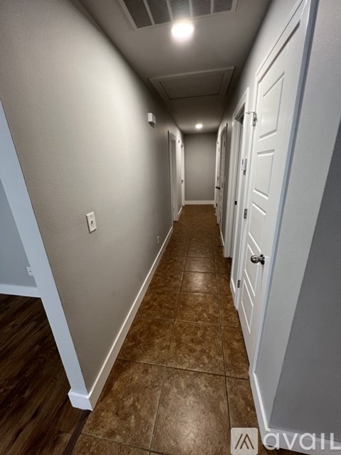 A long hallway with brown tile floors and white walls.