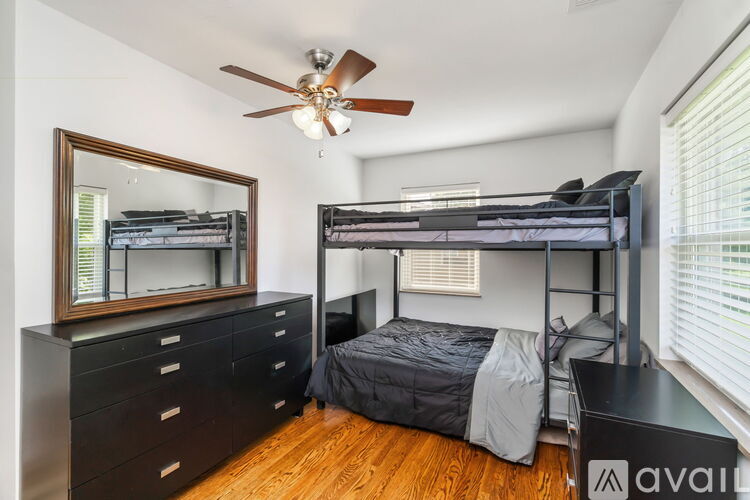 A bedroom with a bunk bed and a dresser with a mirror.