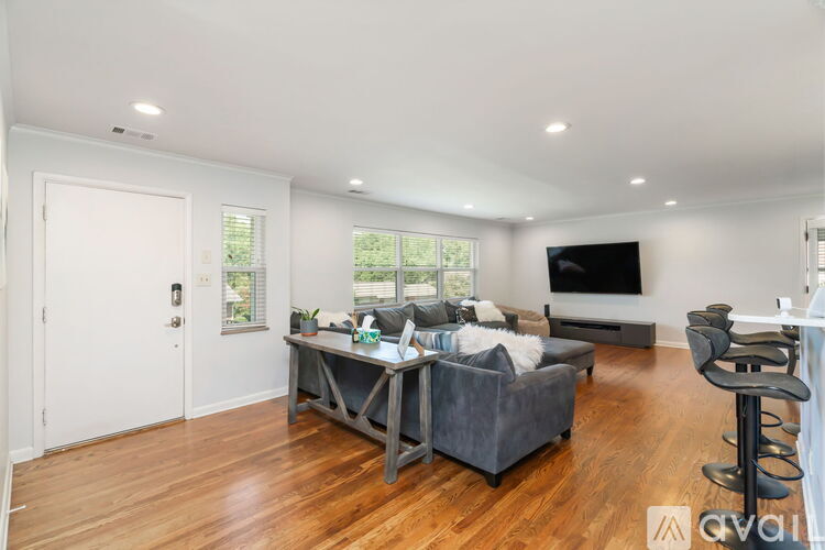A living room with a grey couch and a television on the wall.
